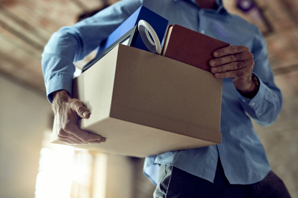 Homem carrega uma caixa com pertences após ser demitido.