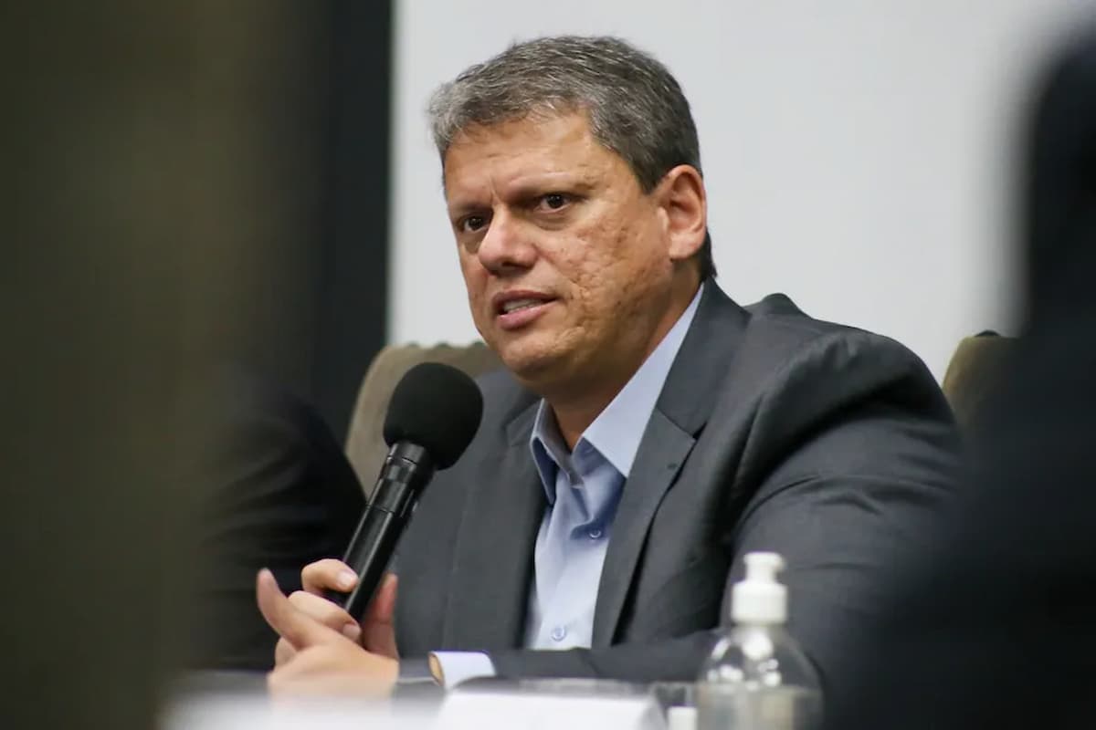 Governador de São Paulo, Tarcísio de Freitas, segura um microfone enquanto fala em uma entrevista.