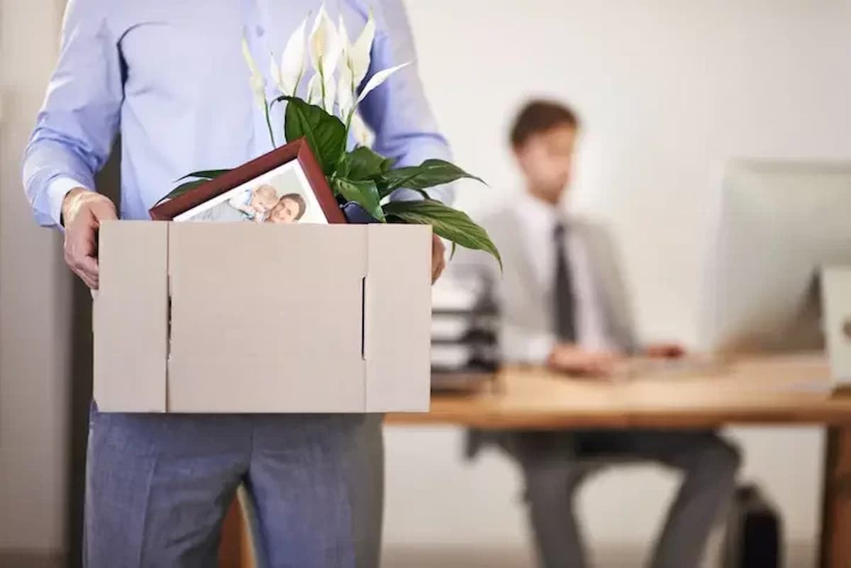 Funcionário levando seus pertences embora dentro de uma caixa de papelão após demissão.