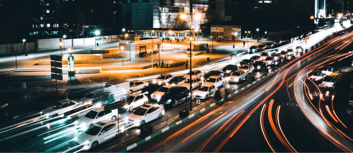 Vista aérea de uma avenida movimentada com trânsito de vários carros durante a noite.
